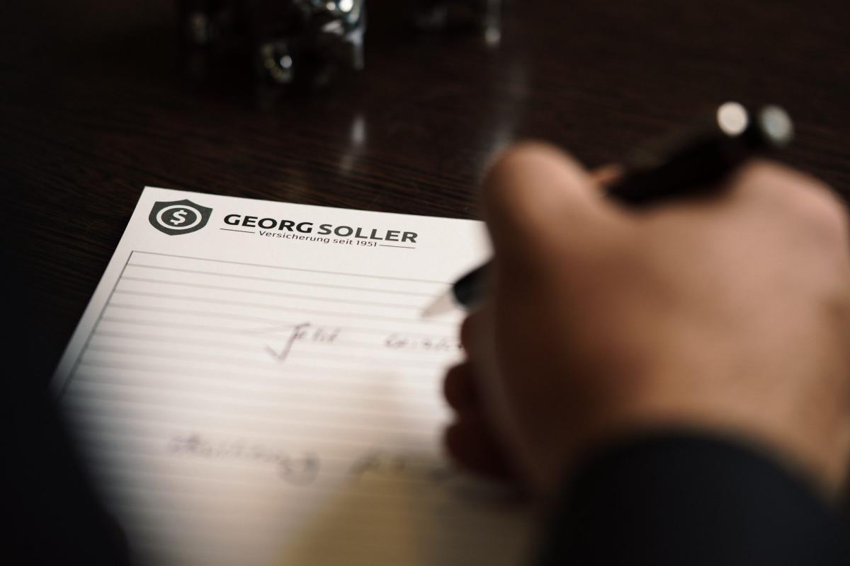 Hand schreibt Notizen zu den steigenden Zuzahlungen 2027.