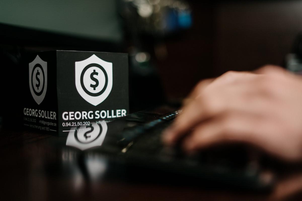 GKV-Beitragsgrenzen als Thema: Georg-Soller-Logo auf einem Laptop, daneben eine Hand auf der Tastatur.
