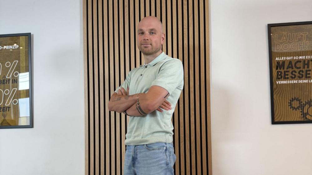 Ein Mitarbeiter der Marketing König GmbH steht vor einer Holzverkleidung und verkörpert die Kundengewinnung für Handwerksbetriebe.