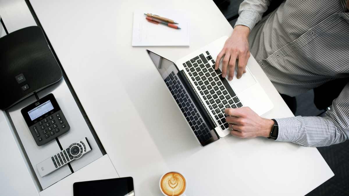 Mann am Arbeitstisch mit Laptop zeigt Skaleneffekte im Unternehmenswachstum.