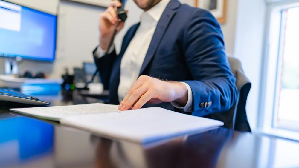 Ein Unternehmer erklärt Skaleneffekte am Telefon während der Büroarbeit.