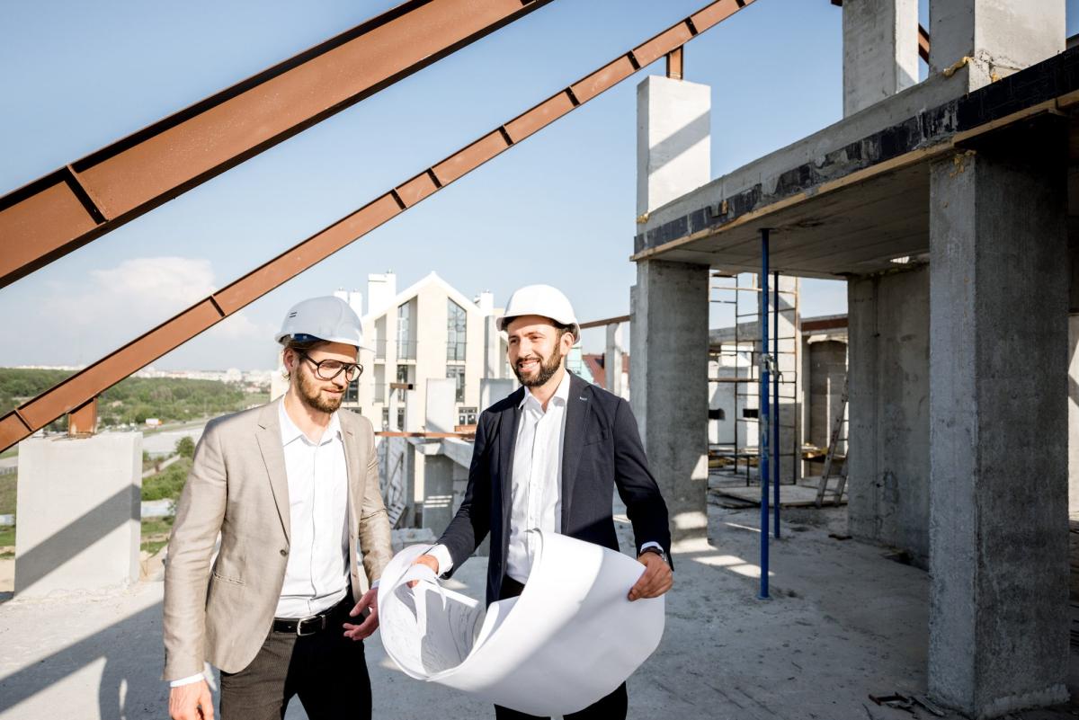 Bauleiter diskutieren über Neubauimmobilien Vertrieb auf Baustelle.