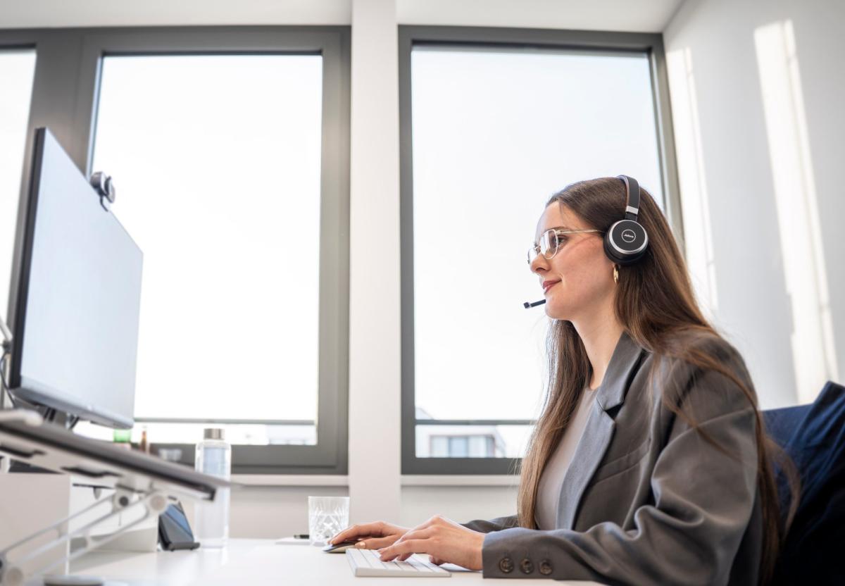 Mitarbeiterin mit Headset arbeitet am Computer zur Lead-Qualifizierung.