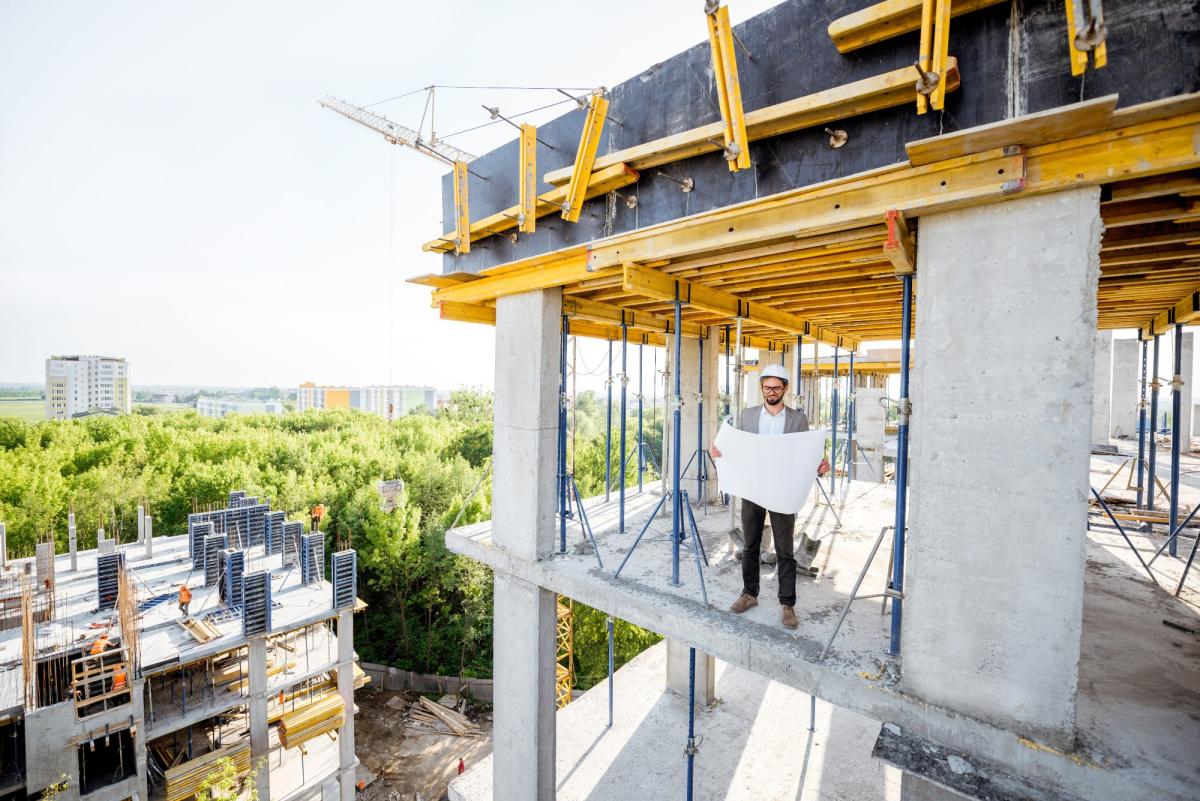 Bauarbeiter präsentiert Bauplan auf einer Baustelle für Neubauprojekte.