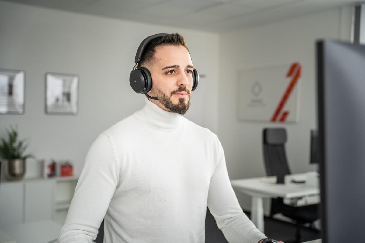 Ein Immobilienmakler mit Kopfhörern arbeitet am Computer, um Interessenten zu finden.