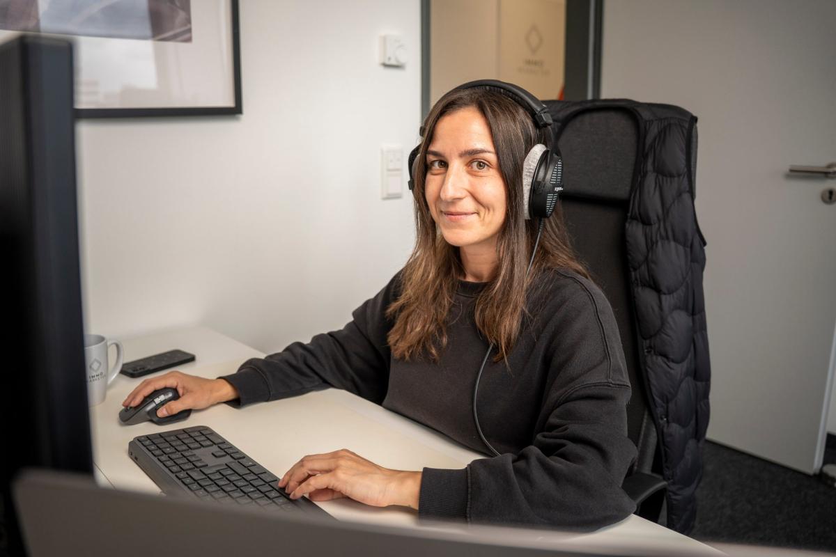 Mitarbeiterin mit Kopfhörern führt telefonische Vorqualifizierung am Arbeitsplatz durch.