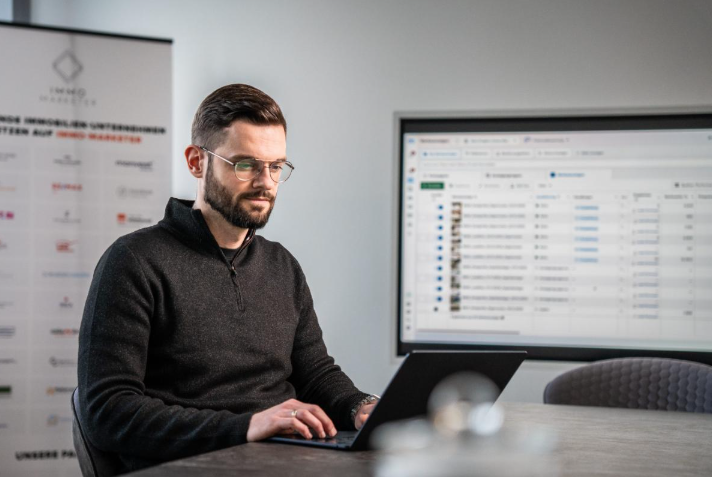 Ein Immobilienmakler arbeitet am Laptop und analysiert Social Media Kampagnen.