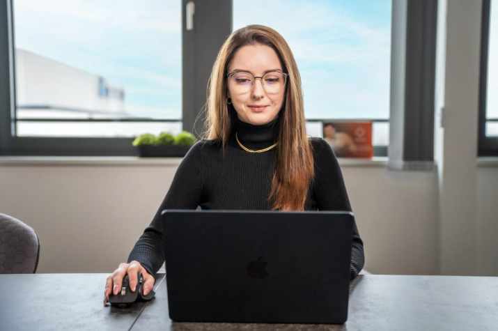 Eine Mitarbeiterin arbeitet am Laptop und optimiert Social Media Marketing für Immobilien.