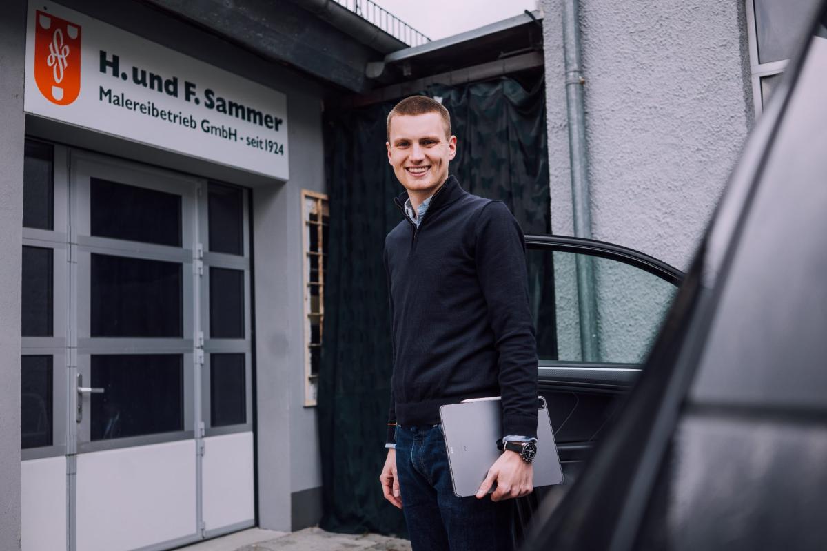 Ein Mitarbeiter steht vor dem Malerbetrieb Sammer und spricht über Fassadenanstrich.