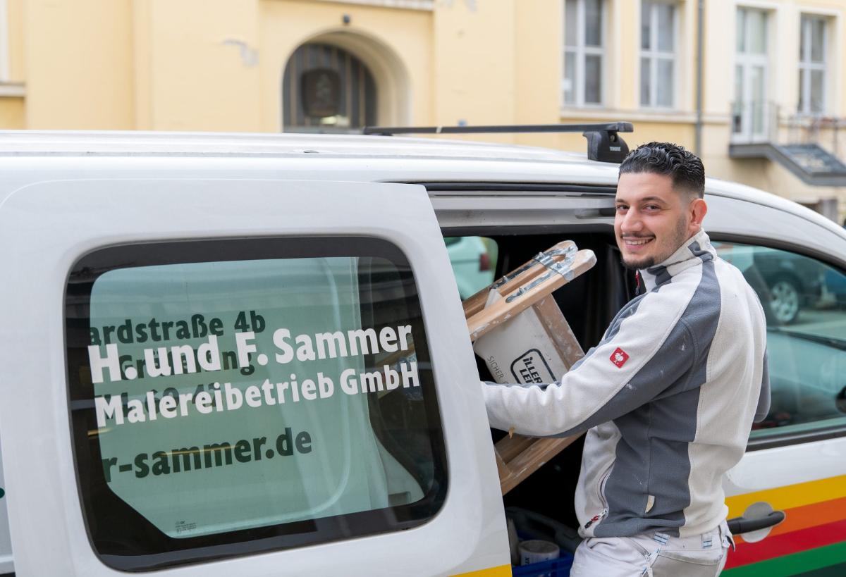 Ein Malergeselle mit Werkzeugen am Fahrzeug für Fassadenanstrich, um den Wert der Immobilie zu steigern.