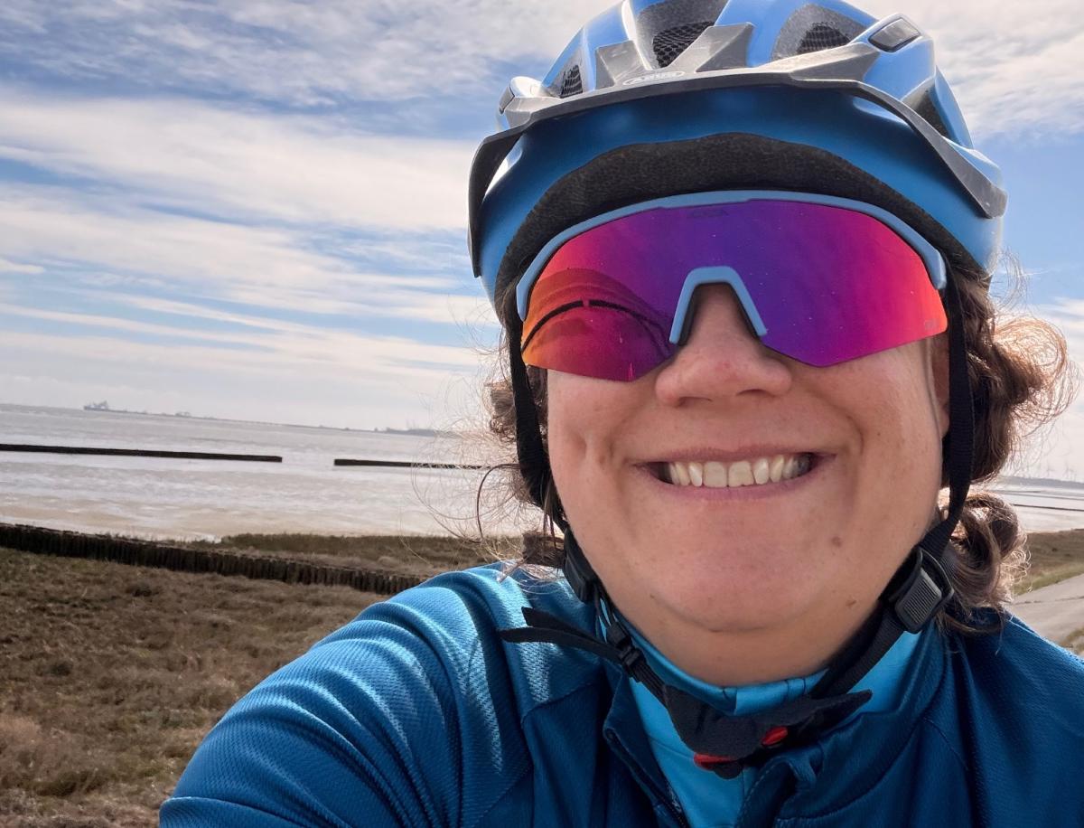 Frau mit Fahrrad und Helm, die sich über Bewegung im Rollstuhl freut.
