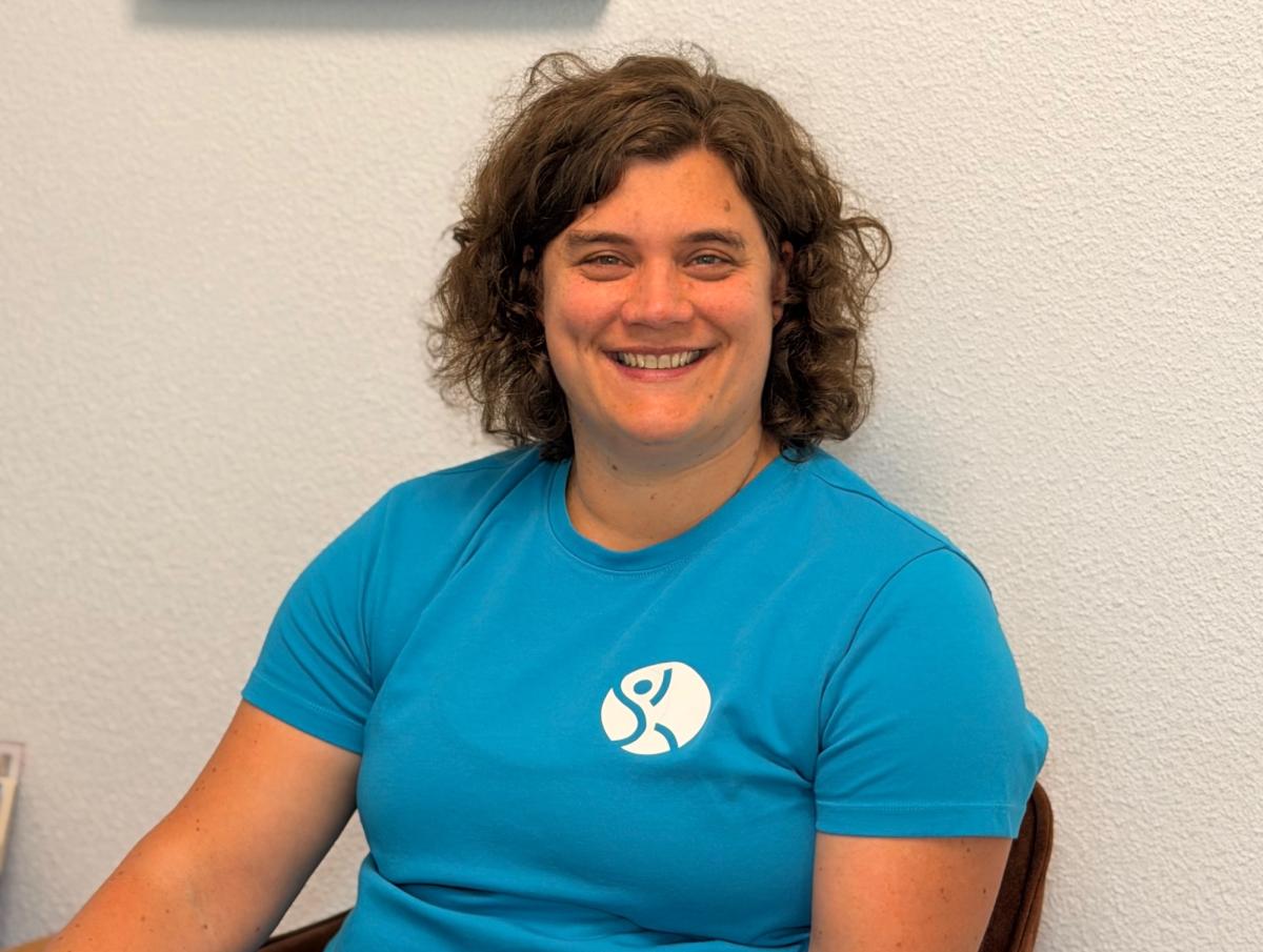 Lächelnde Frau im blauen Shirt zeigt, wie Bewegung nach Unfall helfen kann.