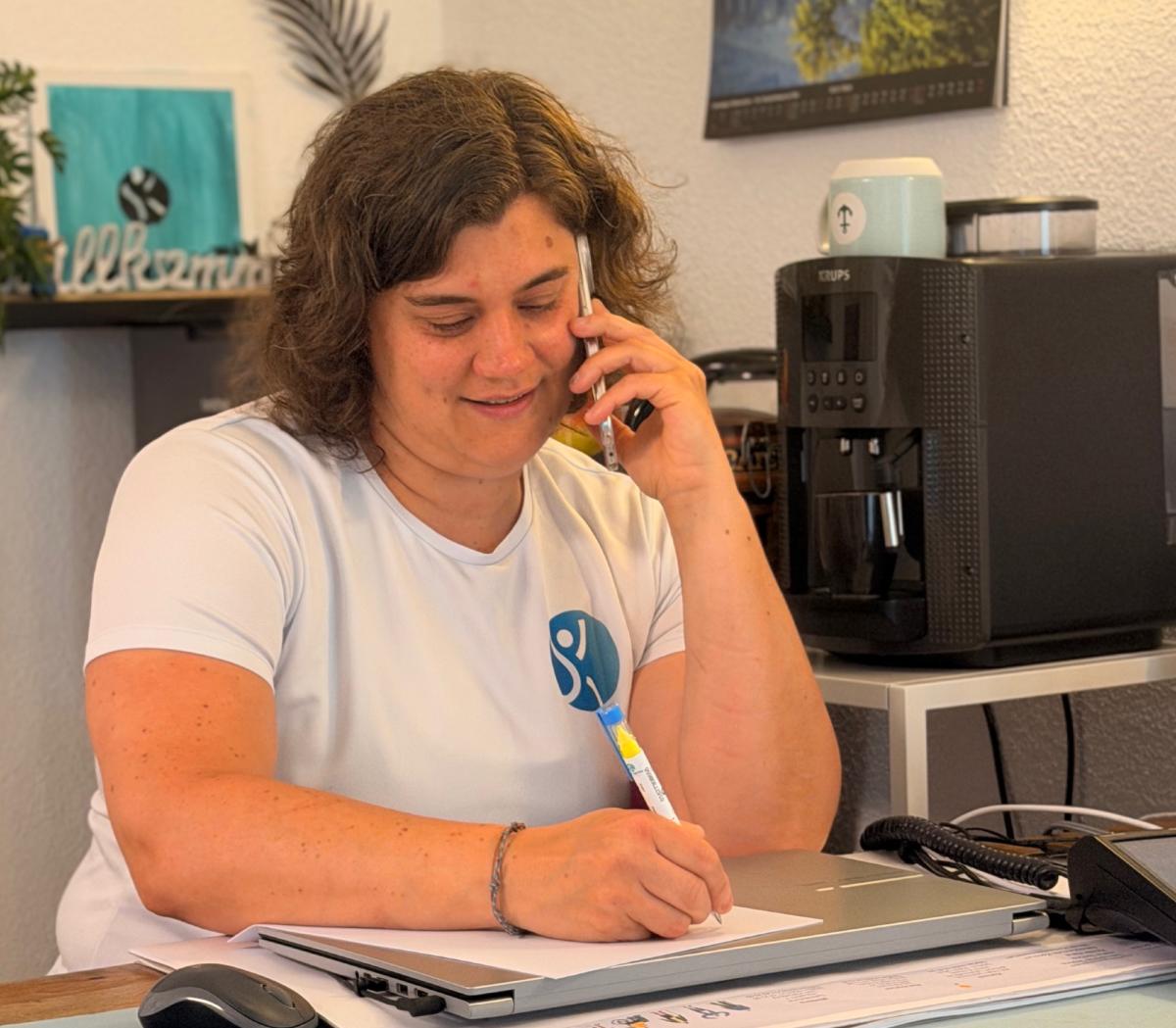 Frau im Büro telefoniert und arbeitet an ihrem 12-Wochen-Plan.