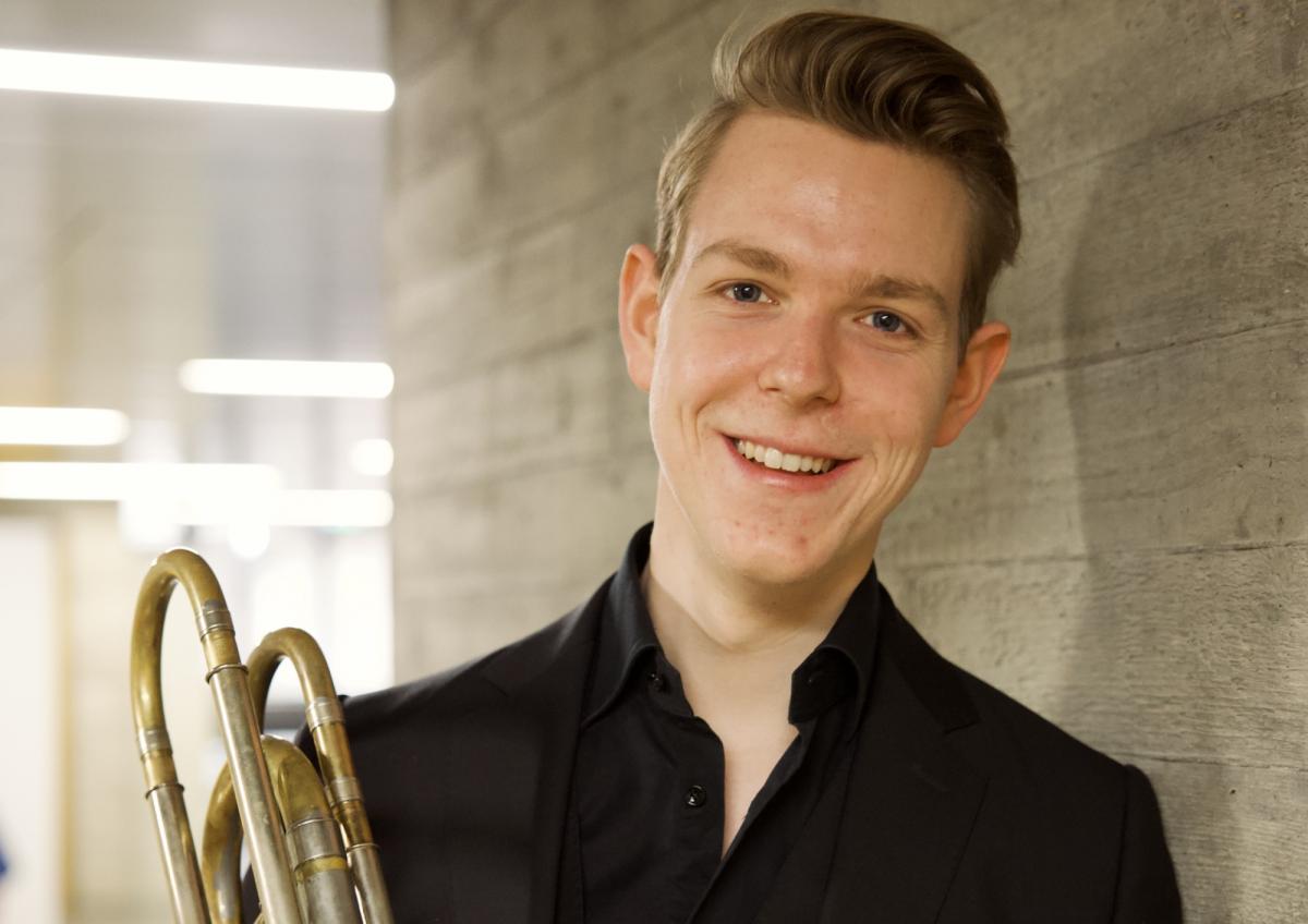 Ein Posaunist lächelt mit seinem Blechblasinstrument und zeigt, wie Blechblasinstrumente für Erwachsene geeignet sind.