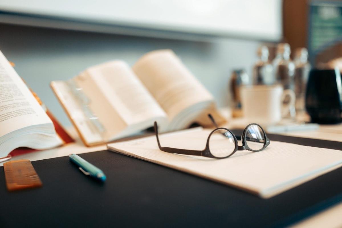 Arbeitsplatz mit Büchern und Brille, symbolisch für Steuerberaterprüfung.