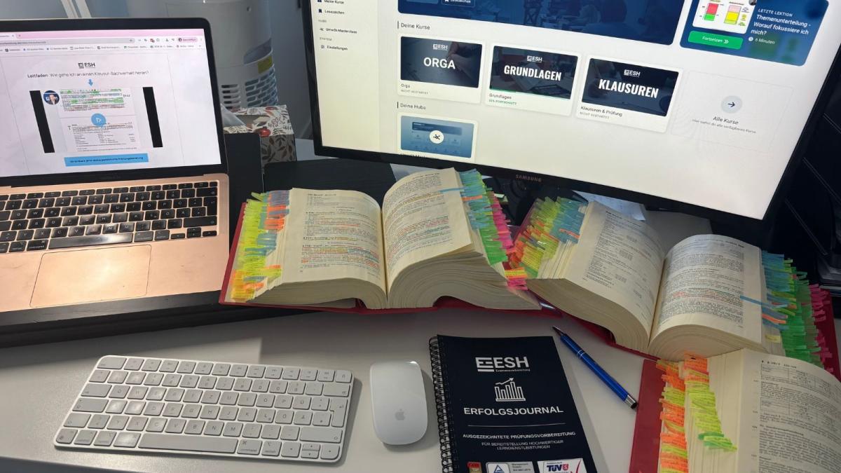 Schreibtisch mit Laptop, offenen Büchern zur Steuerberaterexamen Vorbereitung und bunten Markierungen.