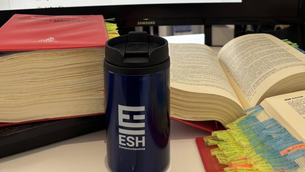 Eine Vorbereitung für das Steuerberaterexamen mit Büchern und einem Becher.