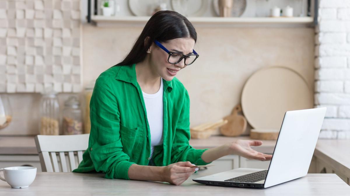 Frau in grünem Hemd debattiert über ETF oder Gold am Laptop.