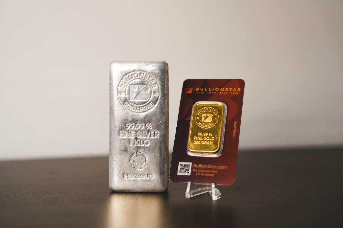 Silberbarren und verpackter Goldbarren stehen auf einem Tisch – passend zum Gold-Silber SWITCH.
