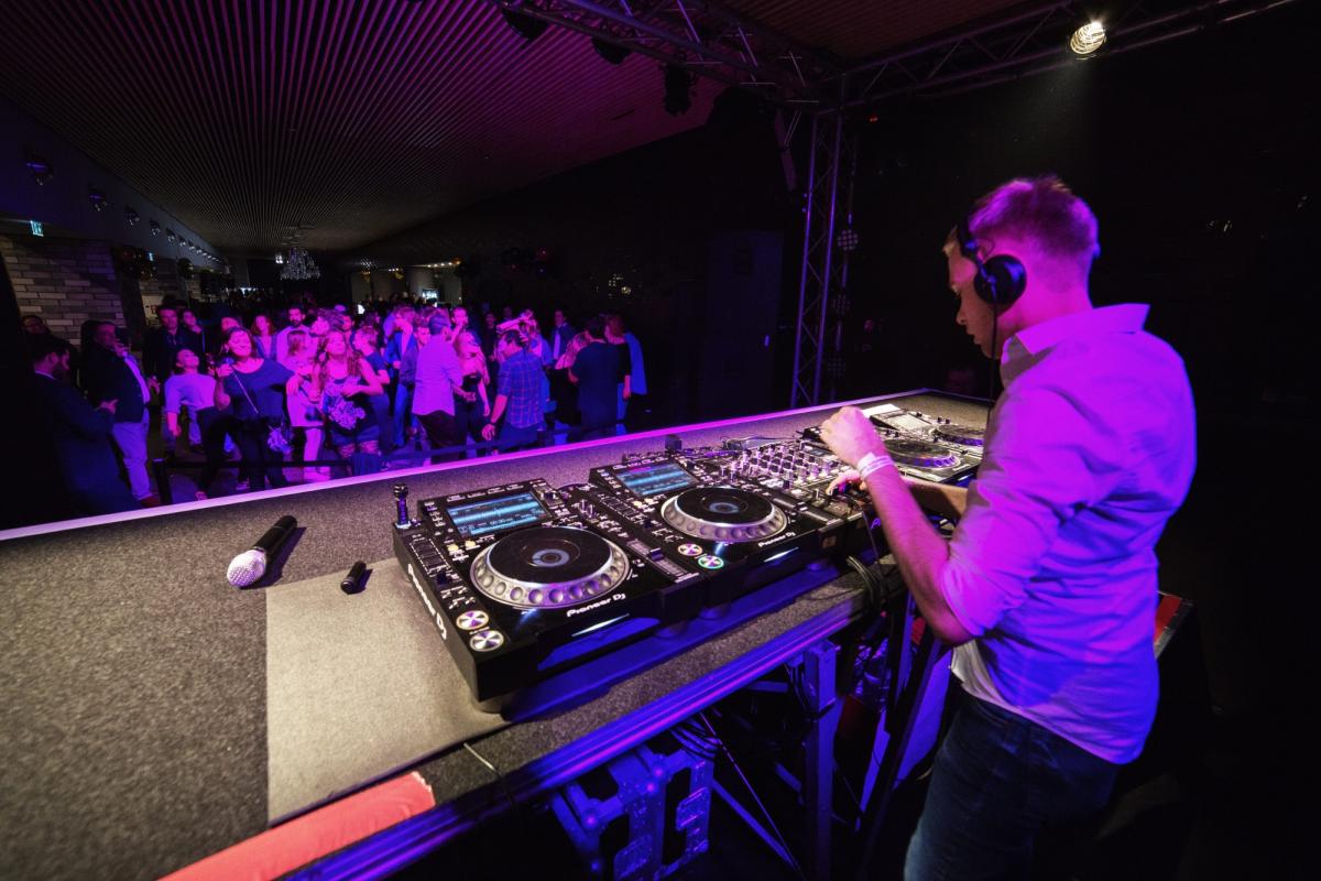 DJ am Mischpult während eines Live-Auftritts mit Publikum.