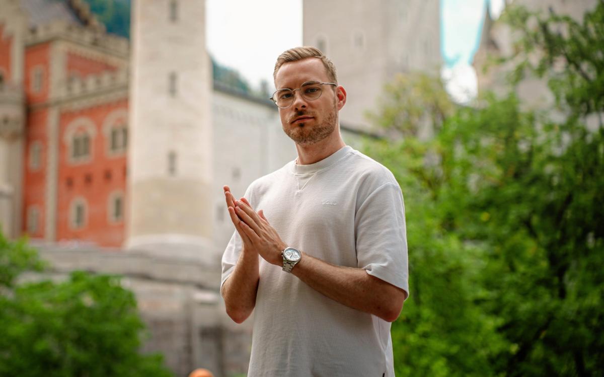 Mann im Freien mit freundlicher Gestik, diskutiert über virale Reels und DJ Bookings.