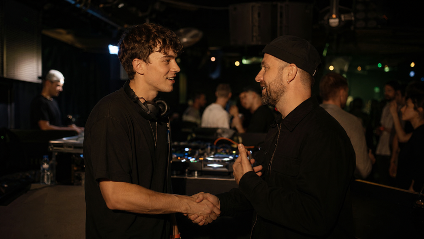 Zwei DJs schütteln sich die Hände und knüpfen Kontakte im Club.