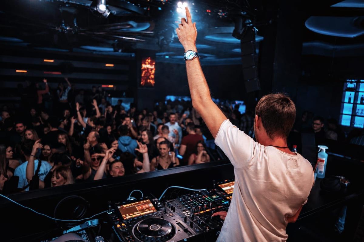 DJ hebt die Hand während einer Party, um die Atmosphäre zu beleben und seine Gage zu optimieren.