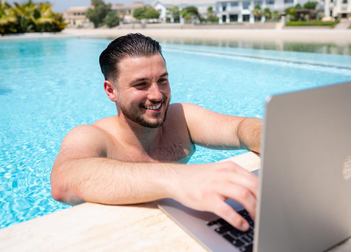 Mann entspannt am Pool und tradet mit Laptop beim Fremdkapitaltrading.