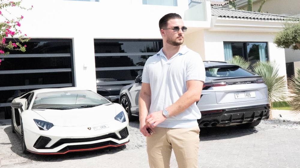 Junger Mann steht mit Luxusautos im Hintergrund für Fremdkapitaltrading.