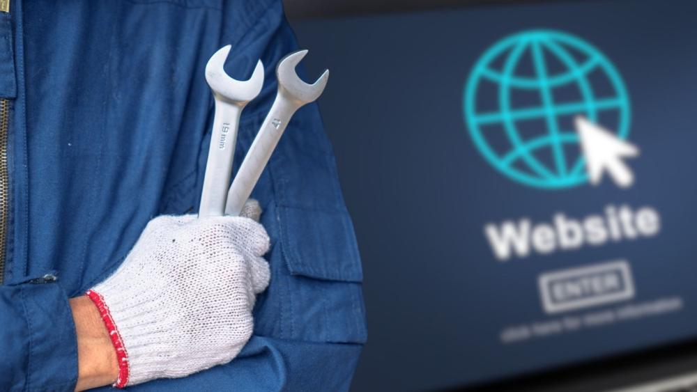 Mechaniker mit Werkzeugen zeigt auf Website-Wartung als Sicherheitsmaßnahme.
