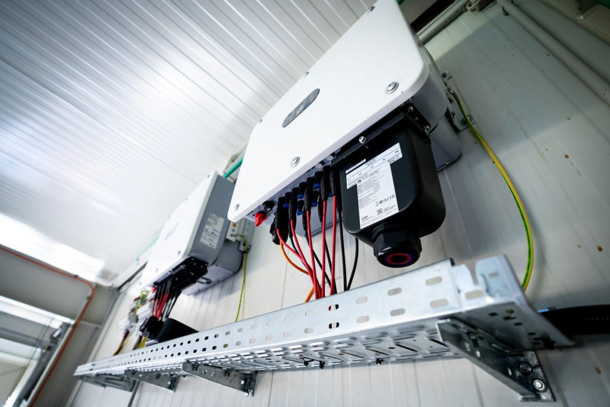 Photovoltaik Anlage mit Wechselrichter und angeschlossenen Kabeln an einer Wand in einem Technikraum